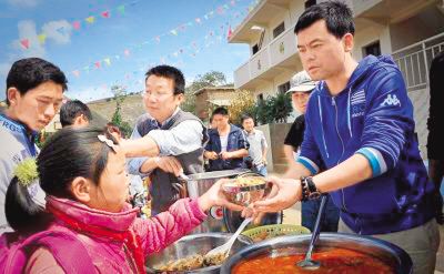 "免费午餐"发起人邓飞(右)为小学生分发午餐.