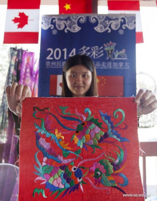 A girl shows a piece of embroidery work with the style of Miao ethnic group during the 'Colorful Guizhou Exhibition' in the Town of Niagara-on-the-Lake, Ontario, Canada, July 22, 2014. 