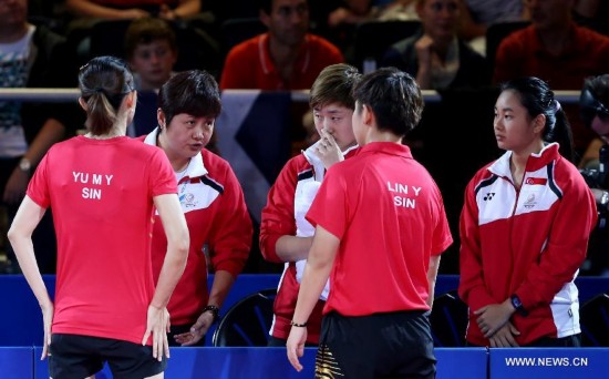 Jing Junhong (2nd L), coach of Singapore, instructs to Lin Ye (2nd R) / Yu Mengyu (1st L) of Singapore during the women's team final of table tennis against Malaysia's Ho Ying/Beh Lee Wei at the 2014 Glasgow Commonwealth Games 