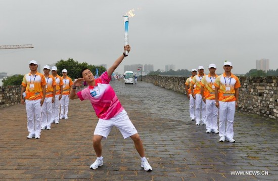Torch bearer Yu Tianyang salutes the Olympic torch on the city wall during the Olympic Torch Relay for the Nanjing Youth Olympic Games in Nanjing