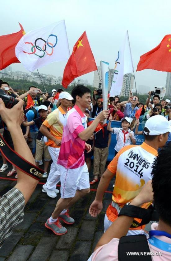 Chinese Olympic fencing Champion Zhong Man acting as the last torch bearer runs on the city wall during the Olympic Torch Relay for the Nanjing Youth Olympic Games in Nanjing