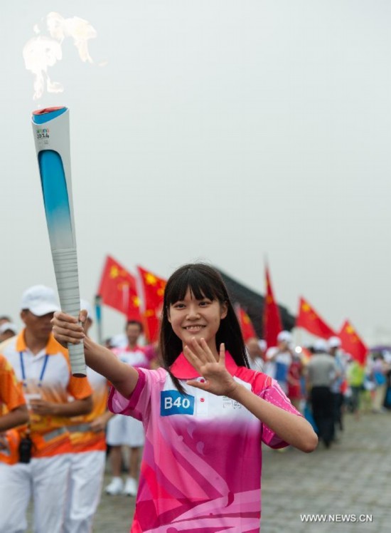 Taiwanese torch bearer Guo Pinli runs with the Olympic torch on the city wall during the Olympic Torch Relay for the Nanjing Youth Olympic Games in Nanjing
