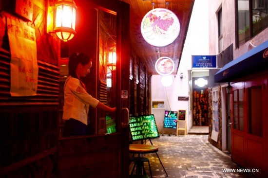 A girl leaves Kevin's Bar at the Chilanqiao cultural block on Shuguangbei Street in Heifei, capital of east China's Anhui Province, August 27, 2014. The cultural block, used to be a hub for junk dealers, has become a favorite destination for artists and culture lovers with its bookstores, galleries, bars and coffee houses and hostels after its reconstruction starting in 2012. (Xinhua/Zhu Weixi)