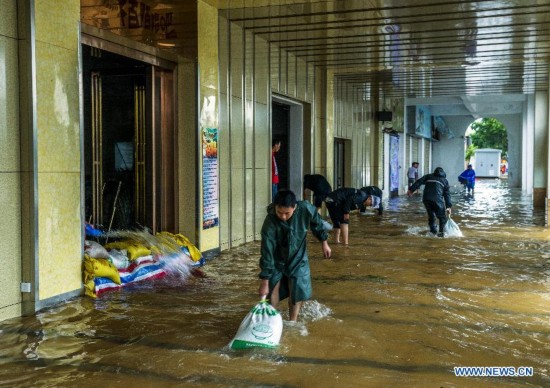 People pile up materials to prevent flood water in typhoon-hit Haikou, capital of south China's Hainan Province, Sept. 16, 2014. Seawater flew backward into the city as typhoon Kalmaegi landed in the island province on Tuesday morning. (Xinhua/Jiang Jurong)