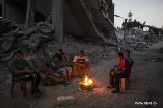 Palestinian men light a fire to illuminate their neighborhood, which was destroyed during the 50-day conflict between Israel and Hamas, in the Shejaiya neighborhood of Gaza City, on Sept 24, 2014. 