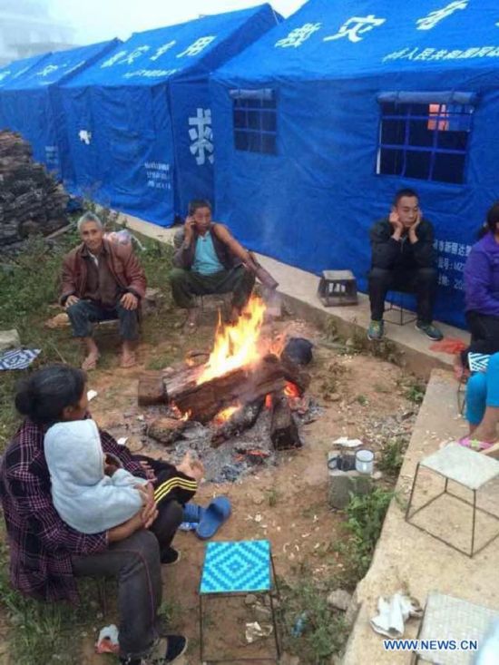 Photo taken with a mobile phone shows the villagers staying outside the tents in Mangfei Village of Yongping Township at Jinggu County of Pu'er City, southwest China's Yunnan Province, Oct. 8, 2014.