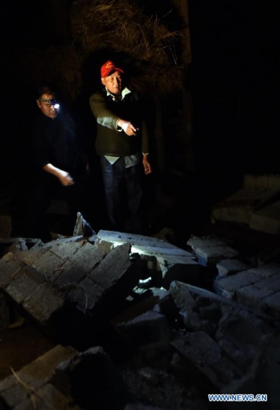 Villager Dao Wenguang (R) looks for his missing family members at Mangla Village of Yongping Township at Jinggu County of Pu'er City, southwest China's Yunnan Province, Oct. 8, 2014.