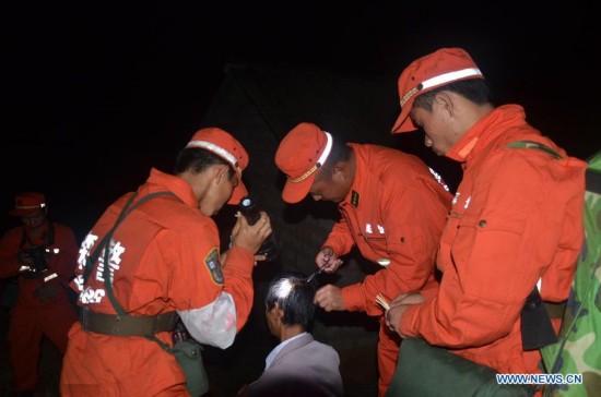 Rescuers treats a wounded villager at Mangla Village of Yongping Township at Jinggu County of Pu'er City, southwest China's Yunnan Province, Oct. 8, 2014.