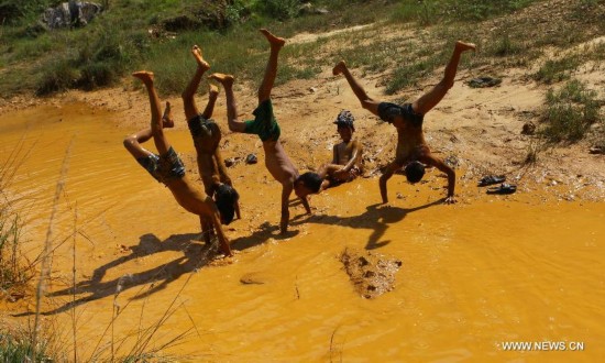 Children show their acrobatic skills while playing in muddy water at Inchangunarayan in Kathmandu, Nepal, Oct. 20, 2014.