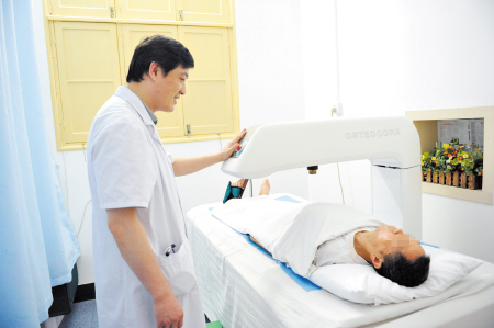 图为长沙市第一医院内分泌科主任欧阳俊正在给患者做骨密度测量,并
