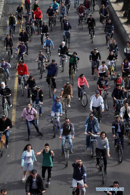 Locals ride bicycles on a street in Damascus, Syria, Nov. 21, 2014, as part of a campaign aimed to raise awareness among Syrians on energy-saving and environmental protection. 