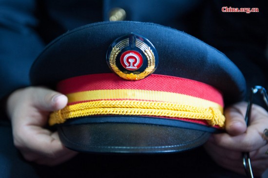 Song Jian holds his cap, saying the badge on the cap means honor to him. [Photo by Chen Boyuan / China.org.cn]