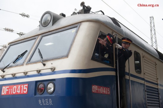 Song Jian (R) and Ding Hailong both confirm the signal visually ahead before the locomotive is set in motion. They say the double confirmation is to ensure complete safety. [Photo by Chen Boyuan / China.org.cn]