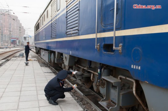 Song Jian (R), the deputy driver of the train T5683 and his master, the chief engineer perform a thorough pre-departure inspection of the locomotive. [Photo by Chen Boyuan / China.org.cn]