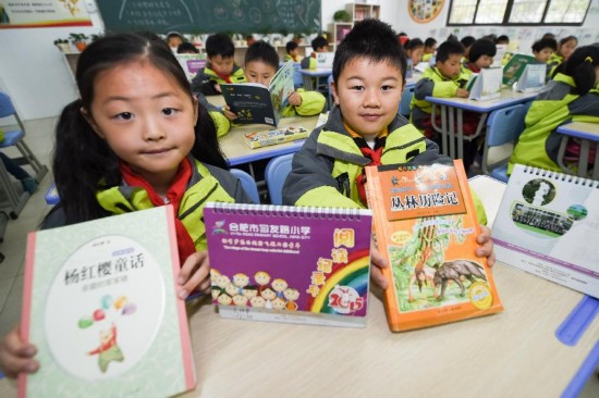 市习友路小学的学生在展示文博苑社区提供的课外书籍和读书心得记录卡