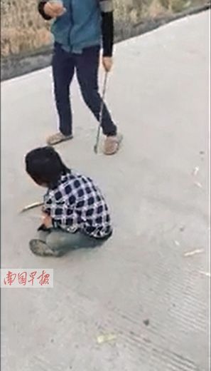 男子一边用竹片打小孩一边拍照.