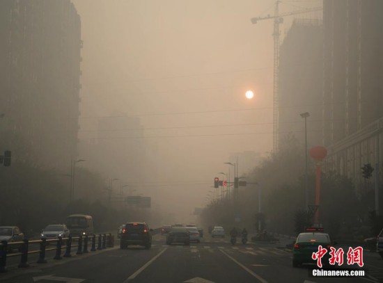 雾霾天气下的高楼,太阳以及马路上行驶的车辆. 刘忠俊 摄