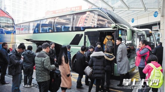 湘江新区综合交通枢纽内,旅客们购票后排队登上长途大巴车.