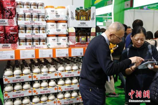 資料圖：首屆中國國際進口博覽會食品及農產品展區，參觀者與商家交流商品信息。中新社記者 殷立勤 攝