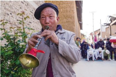 4月10日,赵树芳在农村客事中吹唢呐.