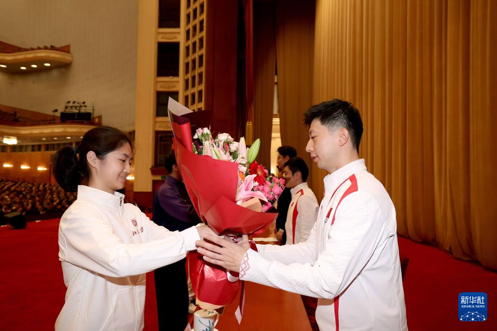 11月15日，一名学生代表在报告会上向乒乓球运动员马龙（右）献花。新华社记者 李明 摄