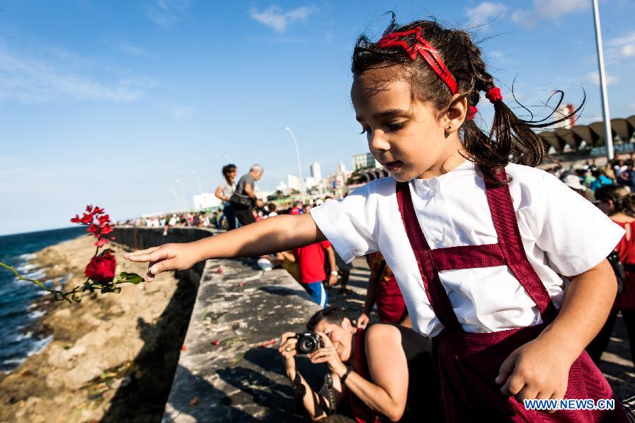 A girl throws flowers into the sea during a ceremny commemorating Camilo Cienfuegos in Havana, capital of Cuba, on Oct. 28, 2014.