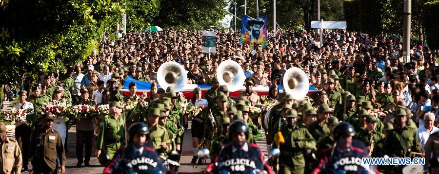 Cubans march from the Revolutionary Square to the seaside to offer flowers to commemorate Camilo Cienfuegos in Havana, capital of Cuba, on Oct. 28, 2014.