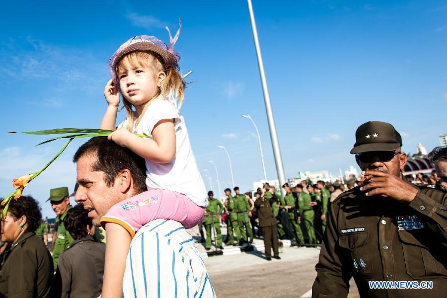 A girl prepares to offer flowers during a ceremny commemorating Camilo Cienfuegos in Havana, capital of Cuba, on Oct. 28, 2014.