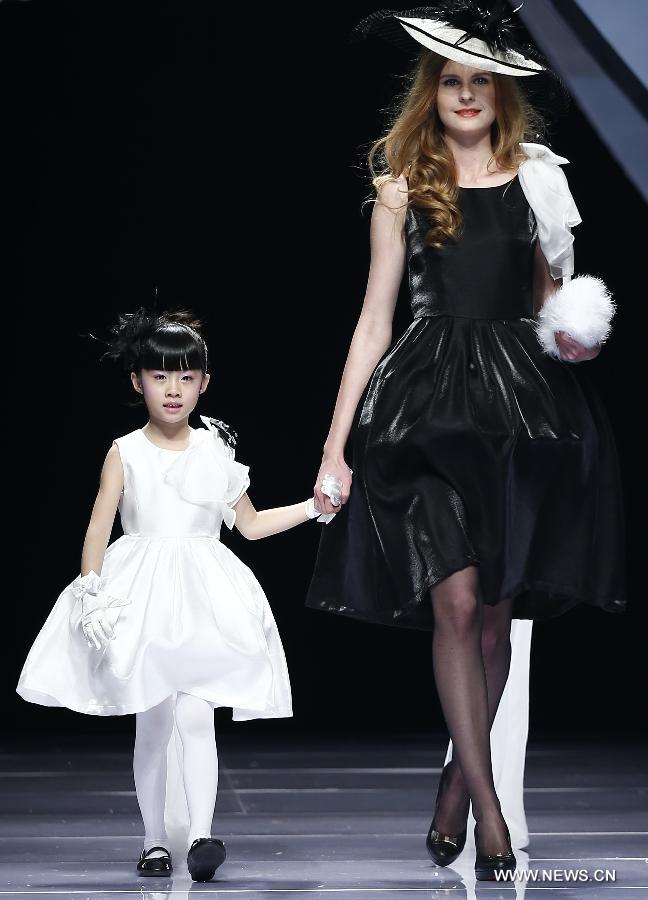 An adult and a child model present creations designed by Dong Wenmei during China Fashion Week in Beijing, capital of China, Oct. 29, 2014. [Xinhua]