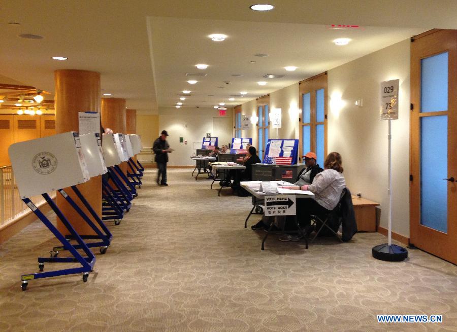 Electoral workers wait for voters at a polling station during the Midterm Elections in New York, the United States, on Nov. 4, 2014. 