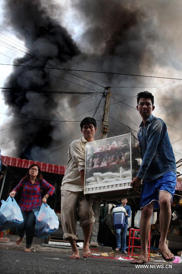 People carry belongings out of a burning market in Phnom Penh, Cambodia, Nov. 24, 2014. 