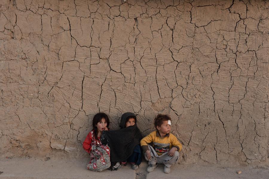 Internally displaced Afghan children look on beside the wall of a mud house in the outskirts of Kabul on November 22, 2014. Afghanistan’s economy has improved significantly since the fall of the Taliban regime in 2001 largely because of the infusion of International assistance. Despite significant improvement in the last decade the country is still extremely poor and remains highly dependent on foreign aid. (Xinhua/AFP Photo)