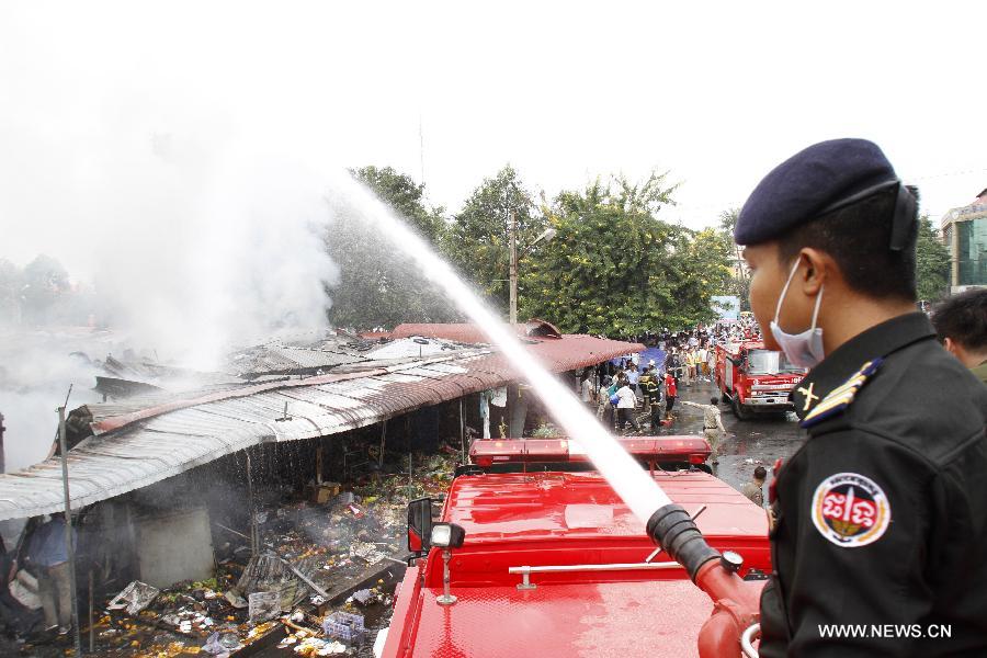 A fire fighter tries to extinguish fire at burning market in Phnom Penh, Cambodia, Nov. 24, 2014. 