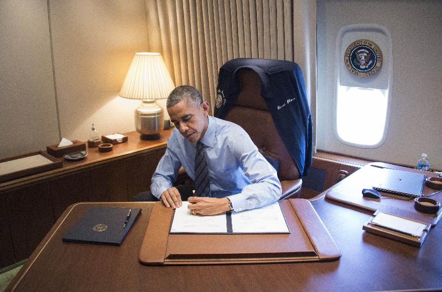 President Barack Obama signs two presidential memoranda associated with his actions on immigration in his office on Air Force One as he arrives at McCarran International Airport in Las Vegas on Nov. 21, 2014.