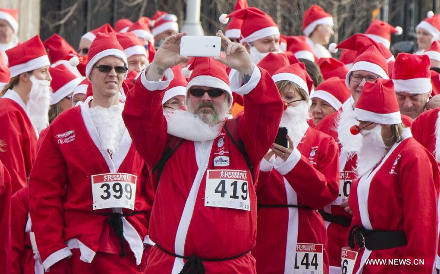 A participant (C) dressed as Santa Claus takes a selfie before the 2014 Santa Race in Hamilton, Ontario, Canada, Nov. 30, 2014. 