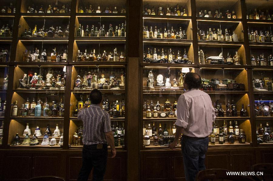 Visitors observe Whisky bottles exhibited in the Museum of Whisky in Buenos Aires, capital of Argentina, on Dec. 4, 2014.