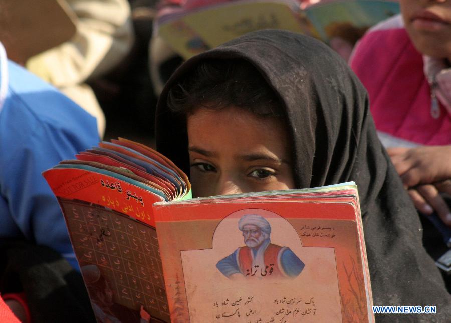 A girl reads a book during a class at a government school in northwest Pakistan's Peshawar, Dec. 11, 2014.