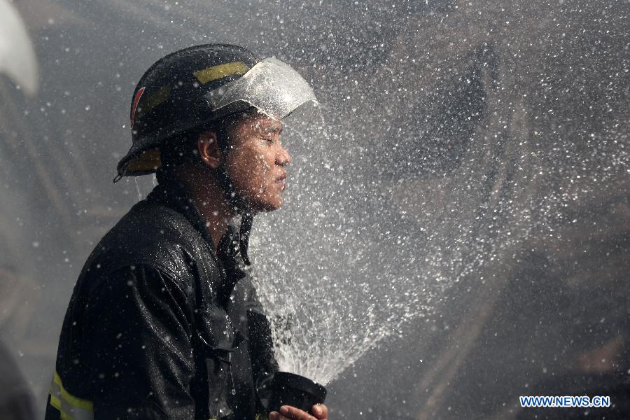 A firefighter sprays water on his face as he puts out a fire that hits a slum area in Manila, the Philippines, Dec. 11, 2014. 