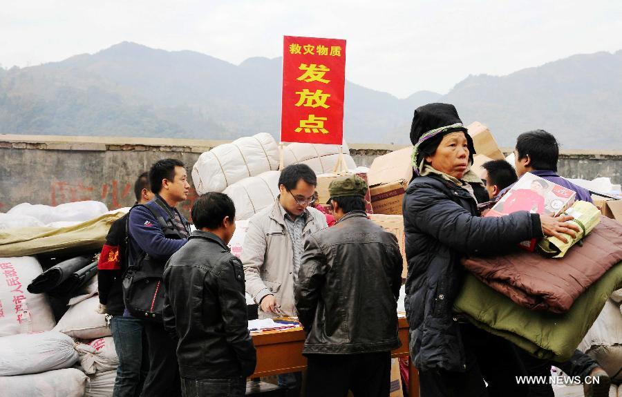 Villagers get relief materials after a fire in Jiuji Village of Jianhe County, southwest China's Guizhou Province, Dec. 14, 2014. A fire engulfed the Jiuji Village at around 3:40 p.m. on Saturday, affecting 619 residents. The relief work is underway. Jiuji is one of the biggest and best preserved villages of the Miao ethnic minority. It was selected by China as a UNESCO World Heritage site nominee in 2006. (Xinhua/Peng Wengui)