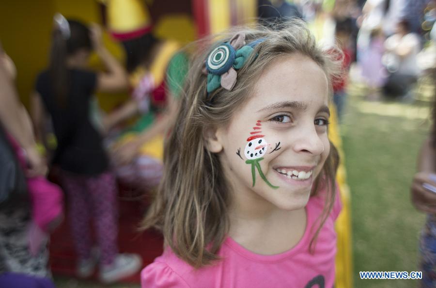 Lucia, 7, poses with Christmas makeup in her face in the Christmas Park in Buenos Aires City, capital of Argentina, on Dec. 21, 2014. (Xinhua/Martin Zabala)