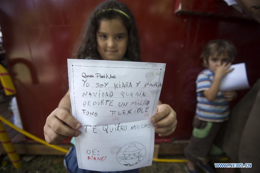 Kiara, 5, shows the letter requesting presents to Santa Claus in the Christmas Park in Buenos Aires City, capital of Argentina, on Dec. 21, 2014. (Xinhua/Martin Zabala)