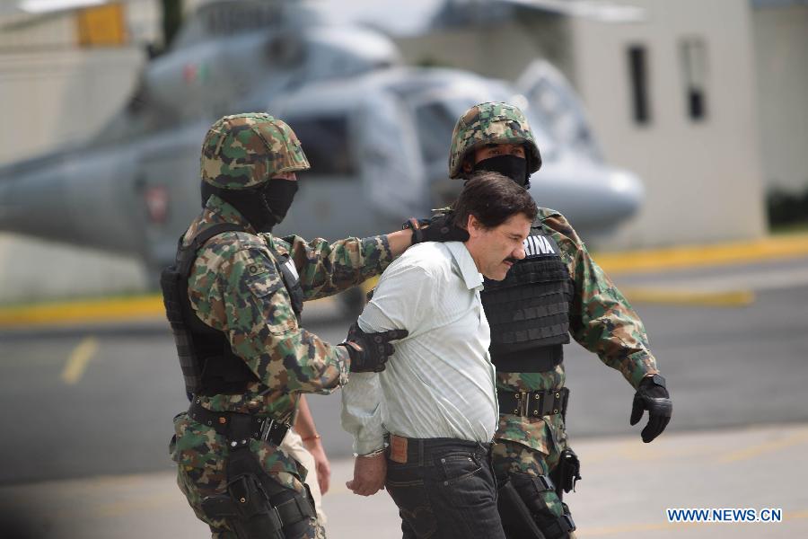 Mexican Navy soldiers escort Joaquin Guzman Loera (1st R), alias 'El Chapo Guzman', leader of the Sinaloa Cartel, during his show in front of the press, at the Mexican Navy hangar in Mexico City, capital of Mexico, on Feb. 22, 2014.