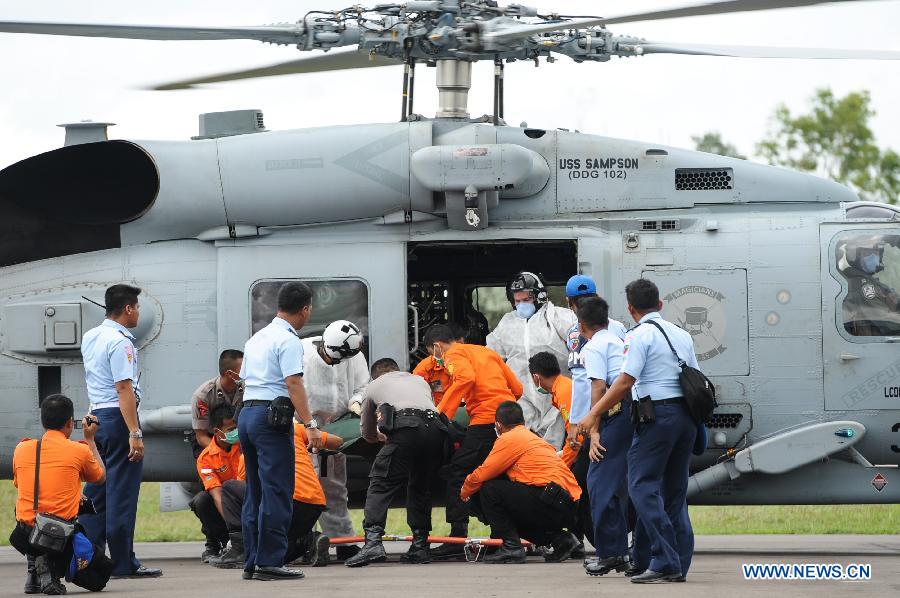 Search and Rescue (SAR) personnel and TNI officer carry the debris of AirAsia flight QZ8501 from a USS Navy helicopter at Iskandar Air Base, in Pangkalan Bun, Central Kalimantan, Indonesia, Jan. 2, 2015.