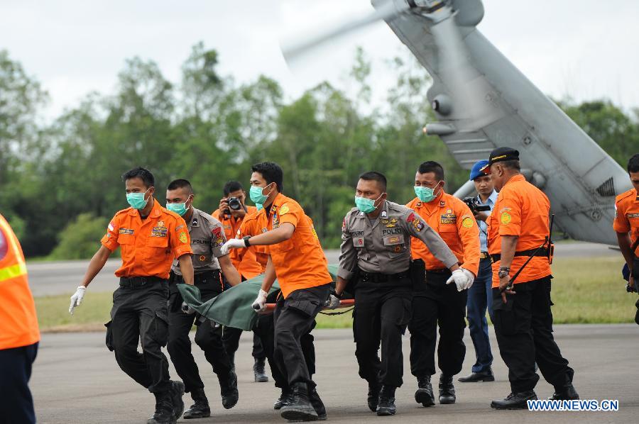 Search and Rescue (SAR) personnels and policemen carry the body of a victim of AirAsia flight QZ8501 from a USS Navy helicopter at Iskandar Air Base, in Pangkalan Bun, Central Kalimantan, Indonesia, Jan. 2, 2015.