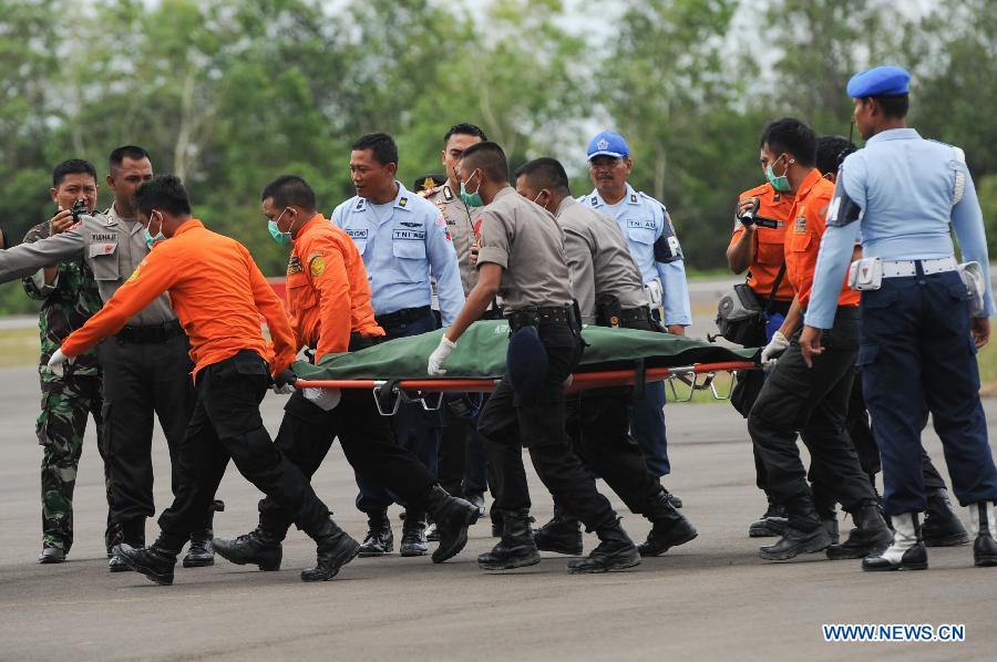 Search and Rescue (SAR) personnels and policemen carry the body of a victim of AirAsia flight QZ8501 from a USS Navy helicopter at Iskandar Air Base, in Pangkalan Bun, Central Kalimantan, Indonesia, Jan. 2, 2015.