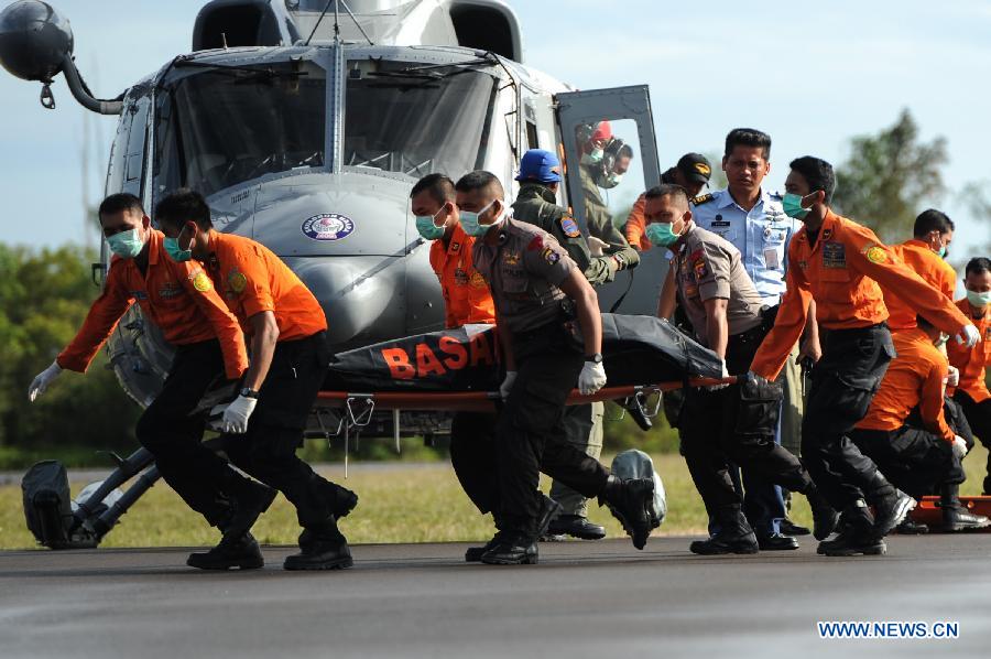 Search and Rescue (SAR) personnel and policemen carry the body of a victim of AirAsia flight QZ8501 from a helicopter at Iskandar Air Base, in Pangkalan Bun, Central Kalimantan, Indonesia, Jan. 2, 2015. 