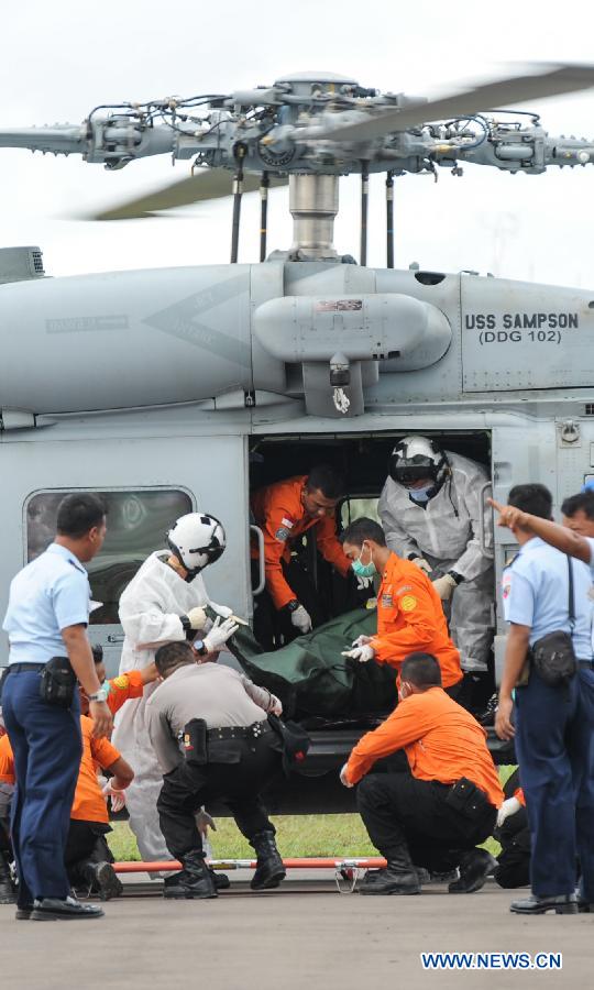 Search and Rescue (SAR) personnel and policemen carry the body of a victim of AirAsia flight QZ8501 from a helicopter at Iskandar Air Base, in Pangkalan Bun, Central Kalimantan, Indonesia, Jan. 2, 2015. 