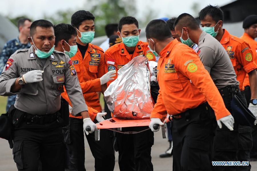 Search and Rescue (SAR) personnels and policemen carry the debris of AirAsia flight QZ8501 from a USS Navy helicopter at Iskandar Air Base, in Pangkalan Bun, Central Kalimantan, Indonesia, Jan. 2, 2015. 