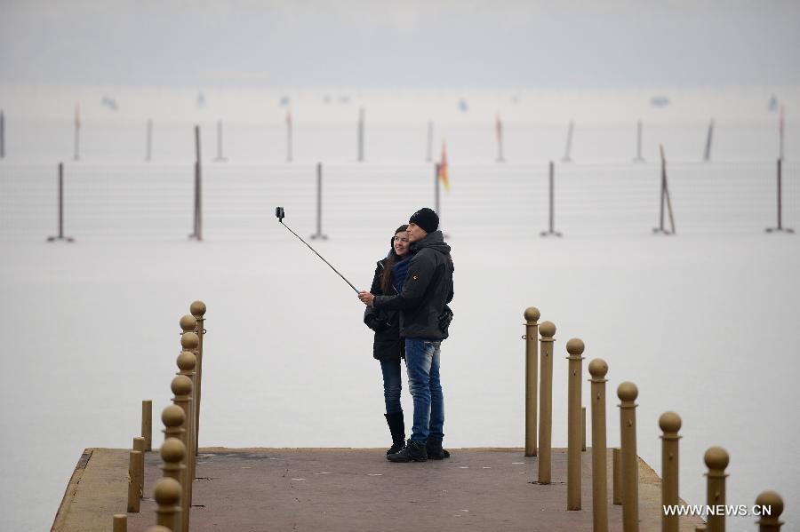 Tourists pose for a selfie with Kunming Lake in the Summer Palace of Beijing, capital of China, Jan. 14, 2015. Beijing on Wednesday saw a snowfall while the city was enveloped by heavy smog. The city's meteorological station recorded snowfall of less than 1 millimeter in the morning, with the snow likely to continue into the evening. (Xinhua/Li Xin)