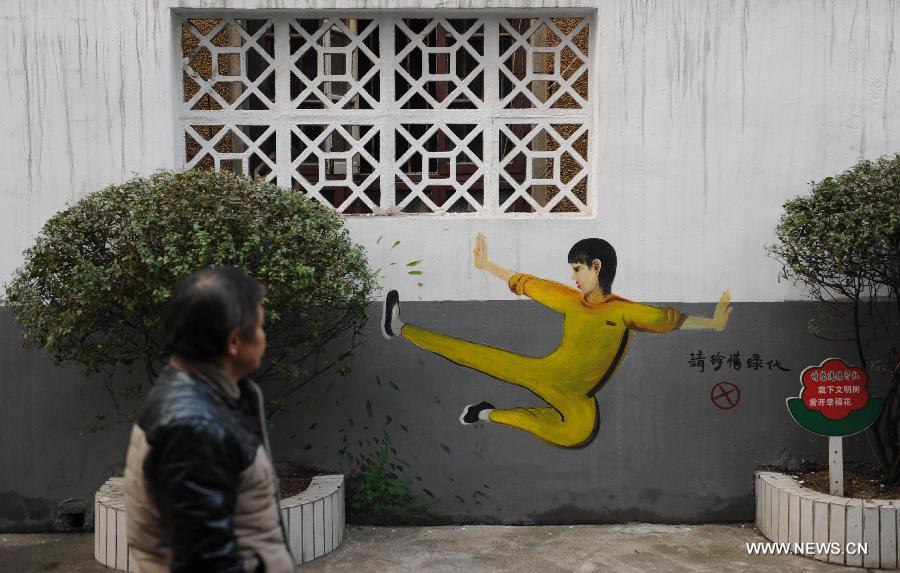 A man walks past a cartoon mural which depicts a martial arts practitioner in a Bruce Lee outfit in a residential community of Changsha, capital of central China's Hunan Province, Jan. 15, 2015. The exterior walls of a residential community in Changsha have been rejuvenated, after a group of young cartoonists were invited to create some 40 cartoon murals on them. The mural painters not only drew on plain walls, but also blended their work with the environment by integrating objects on the scene (newspaper boxes, electricity meter cases, air-conditioning units, etc.) into the murals. (Xinhua/Li Ga)